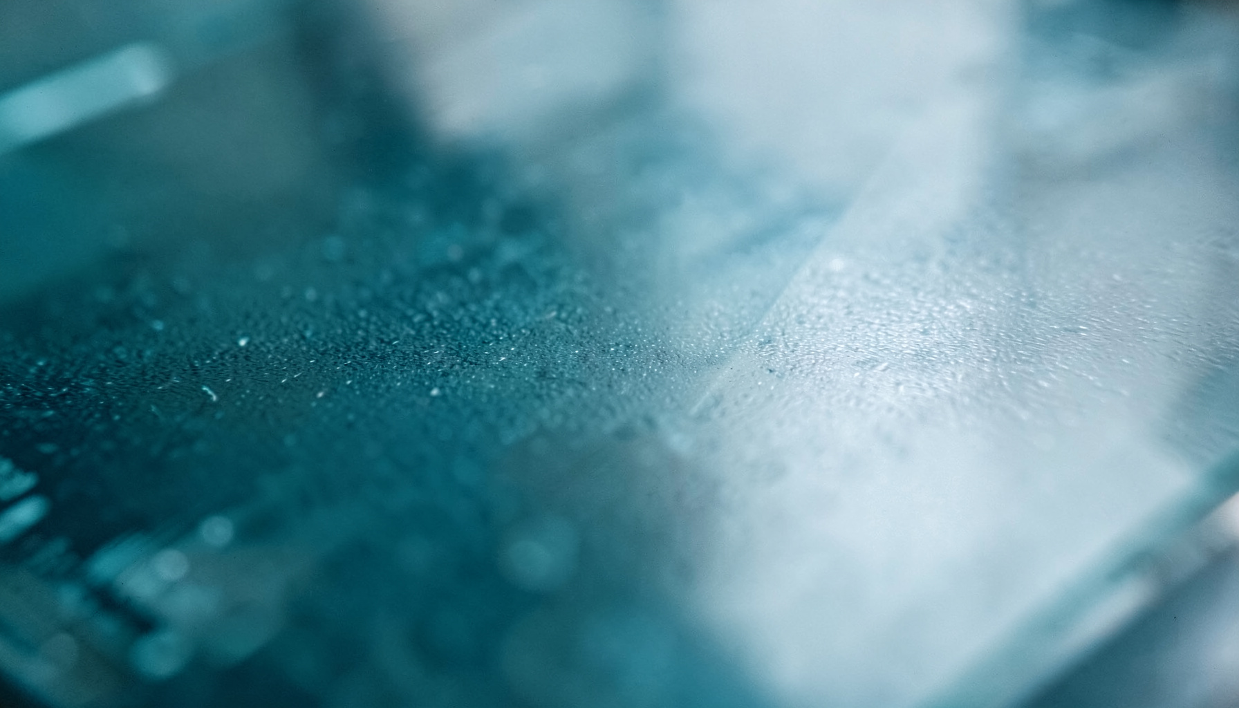 Extreme close-up photograph of a laboratory surface texture, cool blue-gray tones with subtle reflections suggesting glass and stainless steel