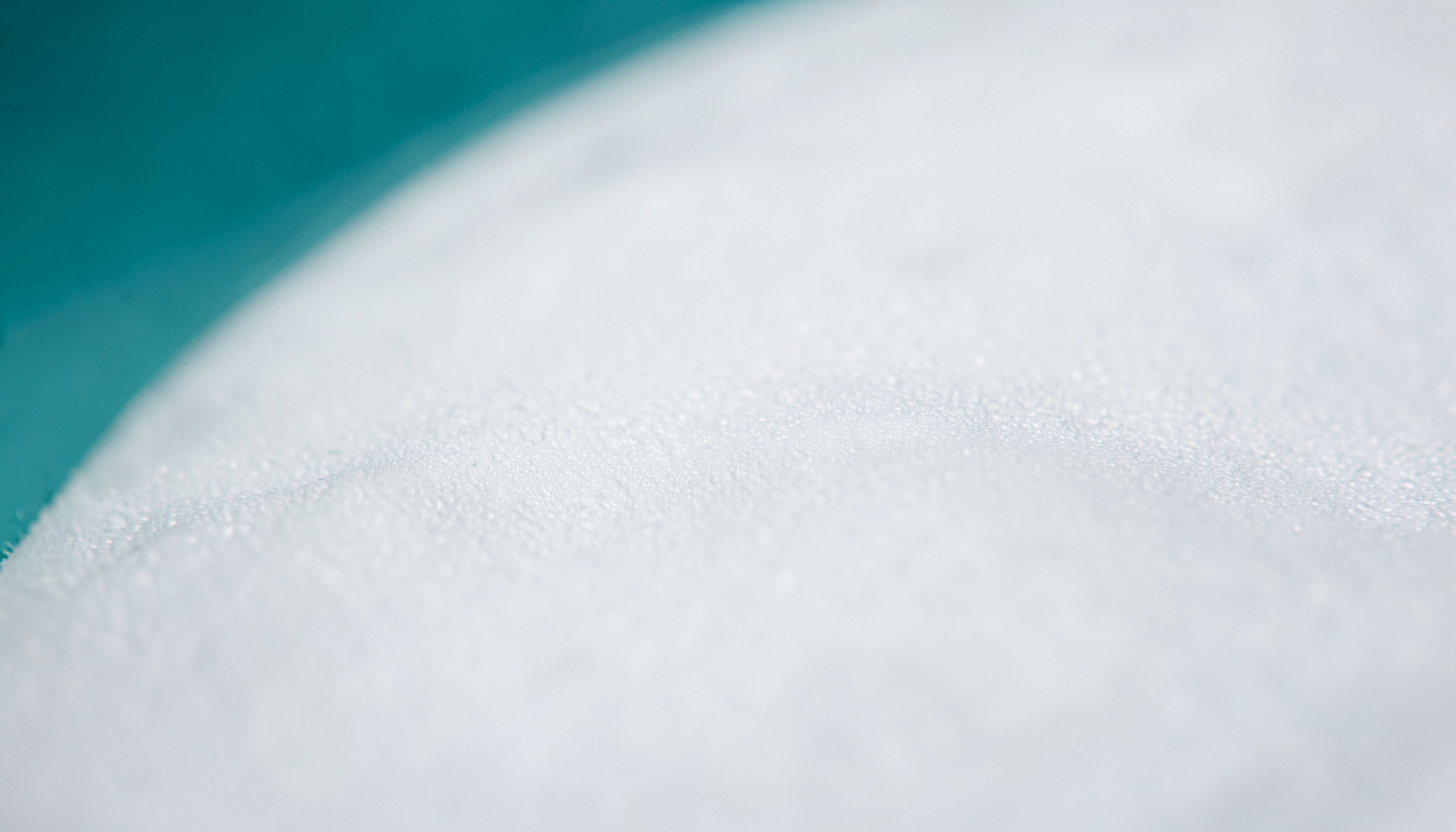 Close-up of a smooth, matte white surface with subtle organic texture, conveying a clean laboratory or pharmaceutical environment